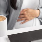 high-angle-pregnant-woman-with-laptop-coffee-mug-working-from-home